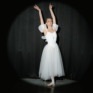 a ballerina performing a move with hers arms extended upwards and one leg behind another.